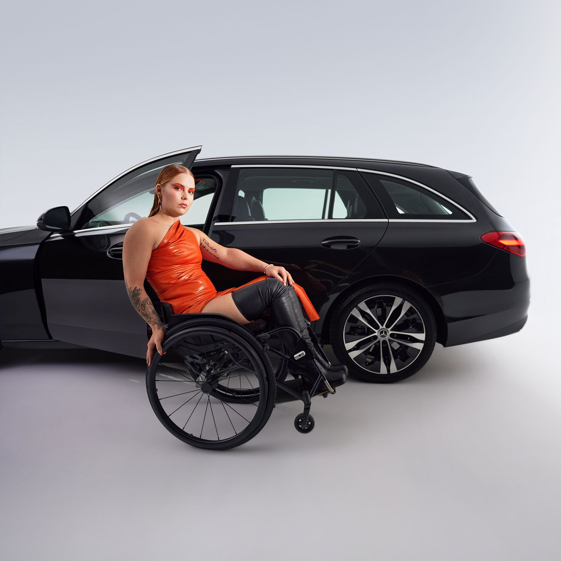 Wspomaganie wsiadania i wysiadania | Układy wspomagania jazdy | Mercedes-Benz Kobieta na wózku inwalidzkim przed czarną Klasą C Kombi Mercedes-Benz.