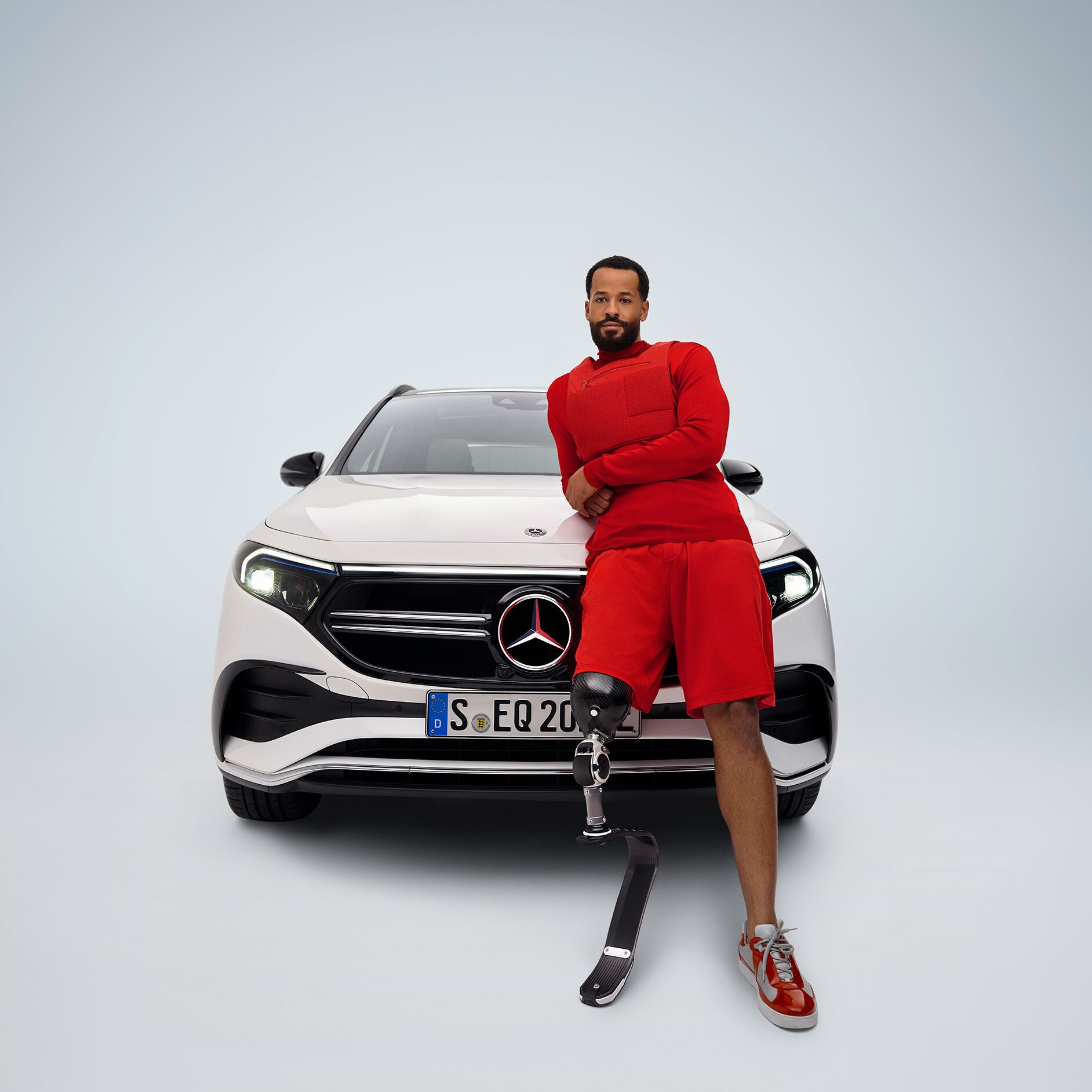 Adaptacja pedałów | Układy wspomagania jazdy | Mercedes-Benz Mężczyzna z protezą nogi opiera się o Mercedesa EQA.