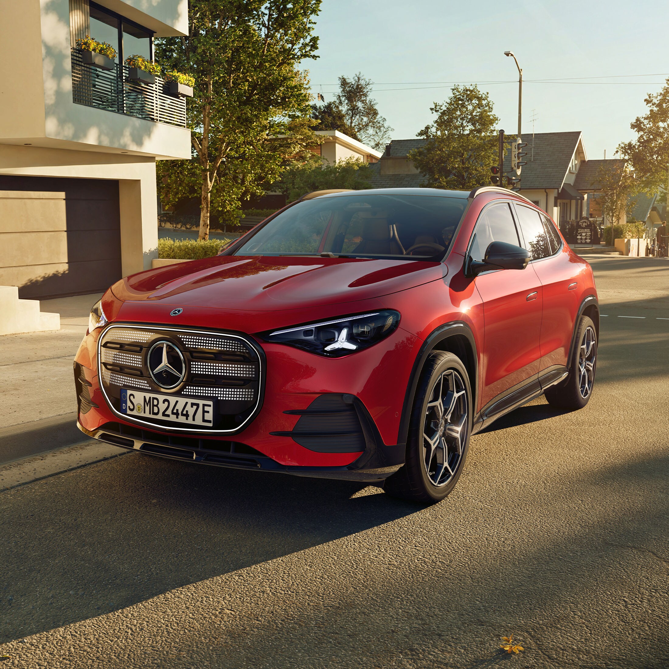 Czerwony Mercedes-Benz GLA electric zaparkowany przed domem.