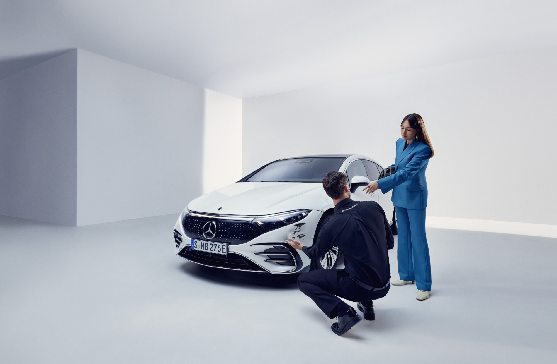 Naprawa szkody | Mercedes-Benz Osoba z Zespołu Wsparcia Mercedes-Benz klęcząca przy uszkodzonym pojeździe Mercedes-Benz.