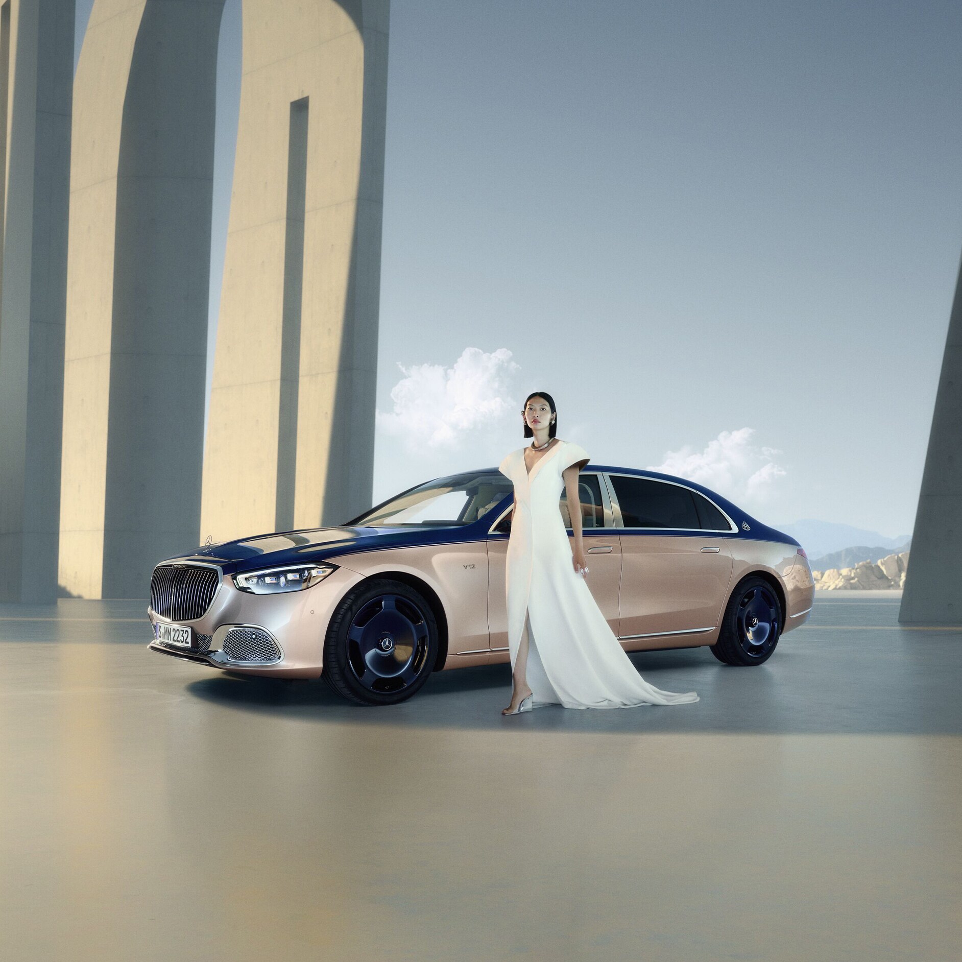 Mercedes-Maybach Kobieta w białej sukni stoi obok Klasy S Mercedes-Maybach.