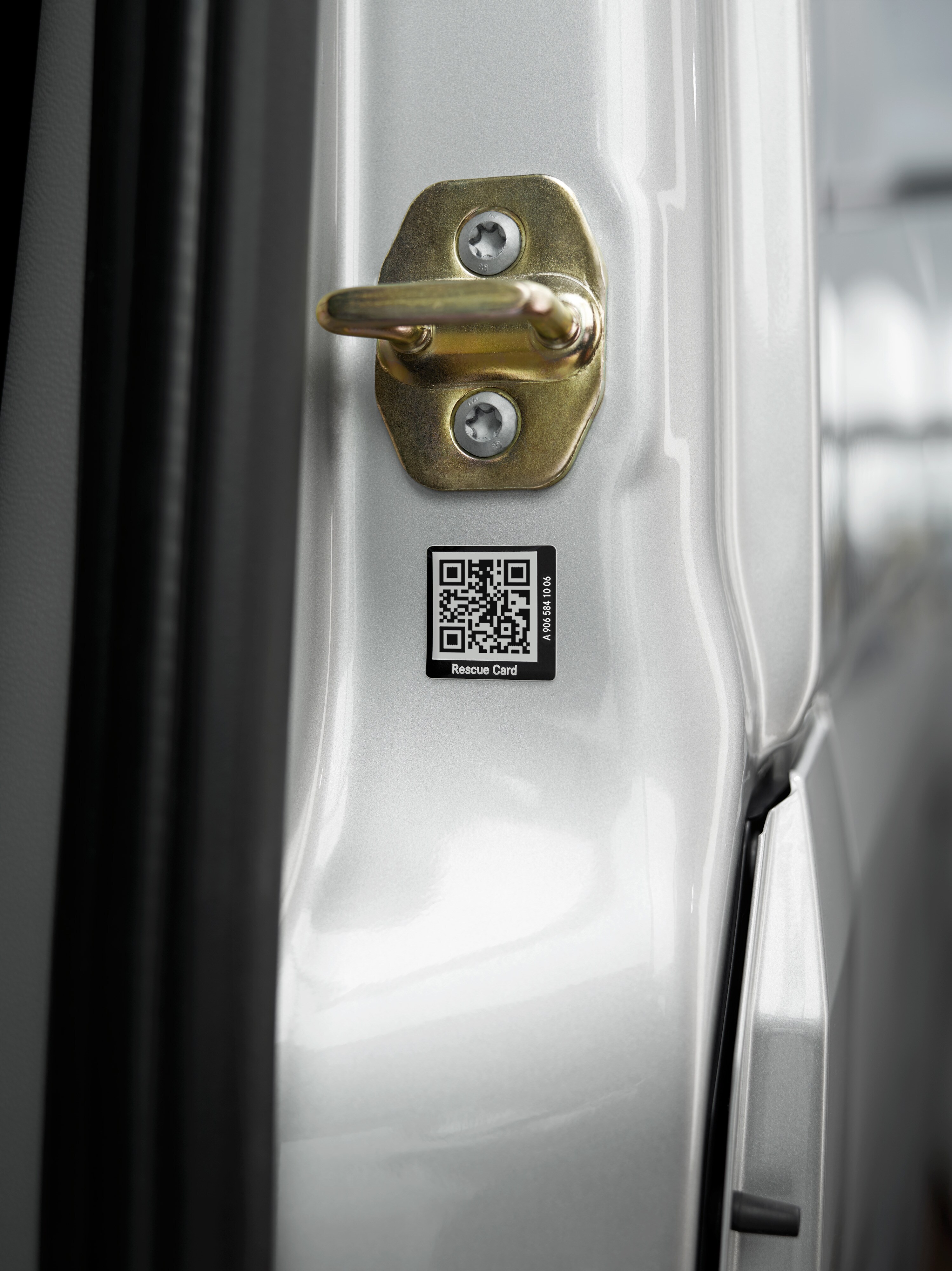 Naklejka ratunkowa Mercedes-Benz Zbliżenie naklejki karty ratunkowej z kodem QR na drzwiach pojazdu.