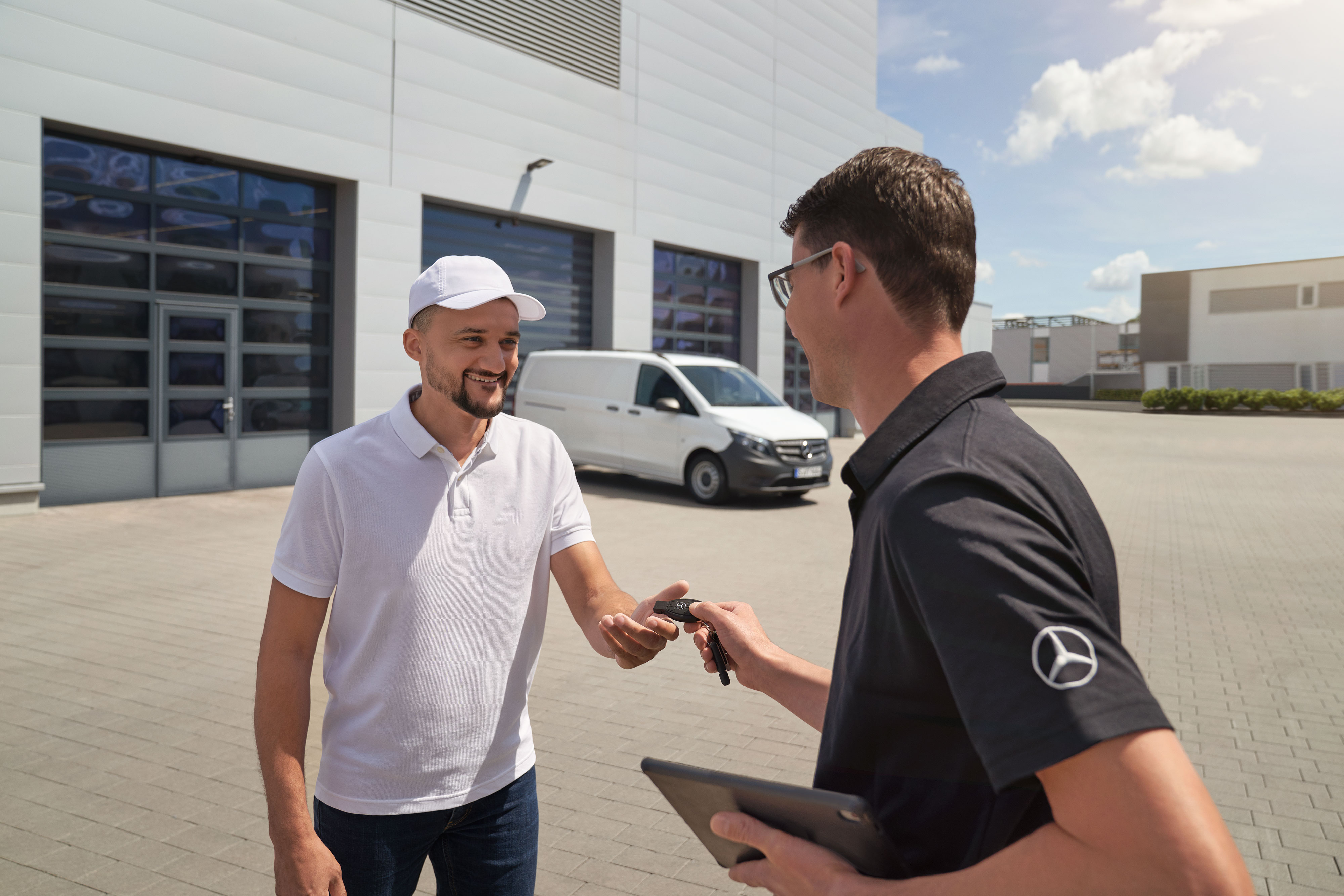 Wygoda | Samochody dostawcze Mercedes-Benz Serwisant Mercedes-Benz przekazujący kluczyki klientowi z białym samochodem dostawczym Mercedes-Benz Vito w tle.