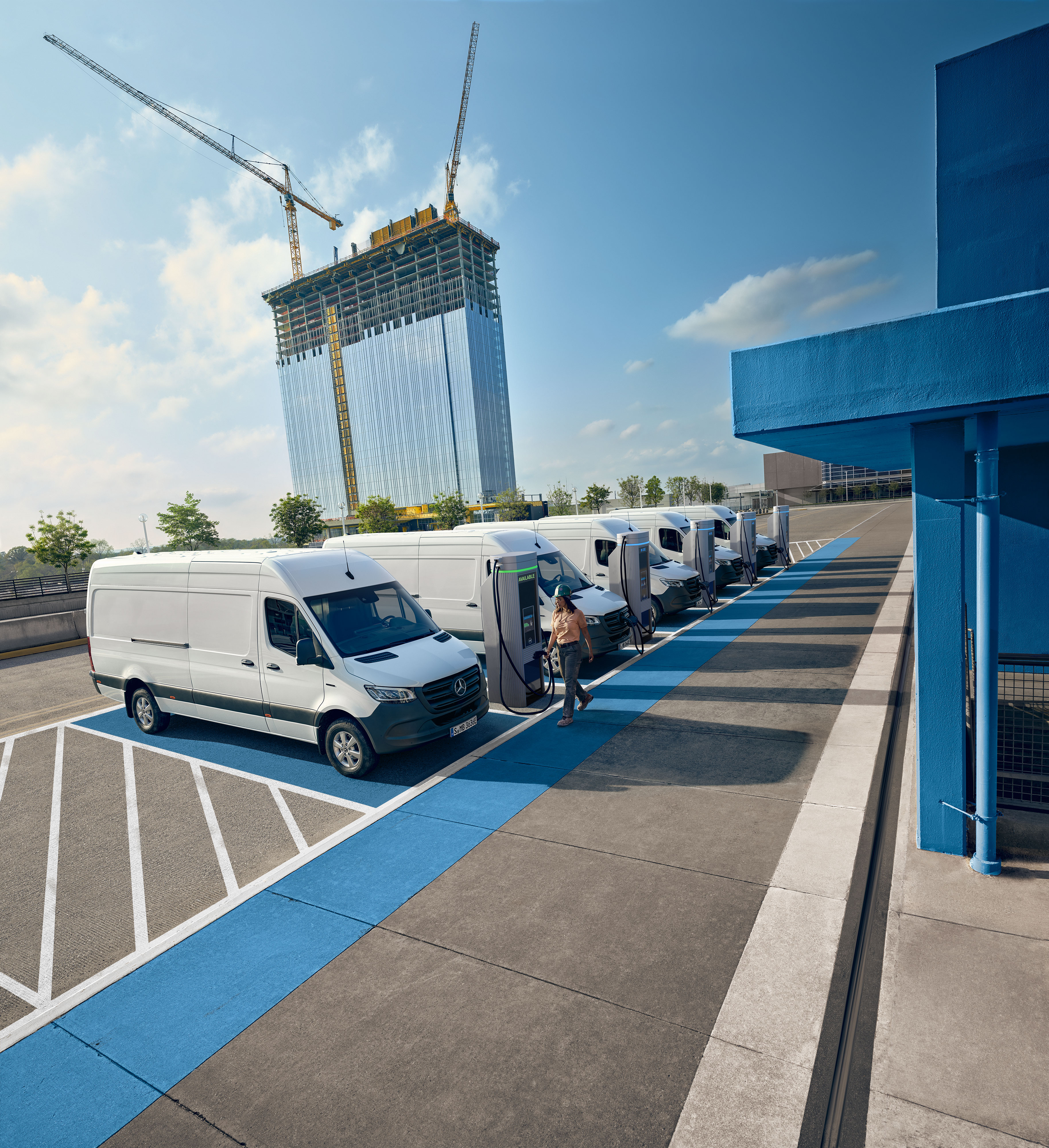 Wygoda | Samochody dostawcze Mercedes-Benz Flota białych elektrycznych samochodów dostawczych Mercedes-Benz zaparkowanych przy stacji ładowania.