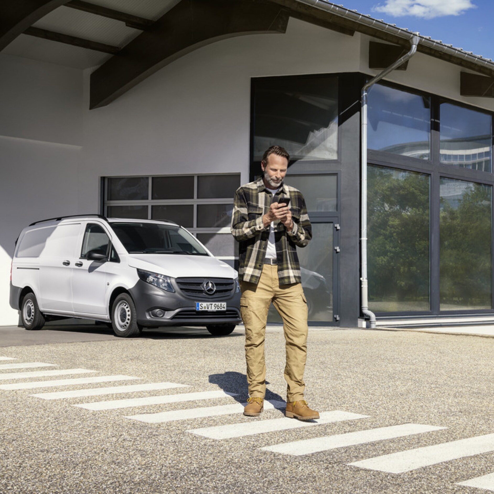 Mercedes-Benz Store | Cyfrowe Dodatki | Mercedes-Benz Osoba trzymająca smartfona przed modelem Mercedes-Benz Vito.