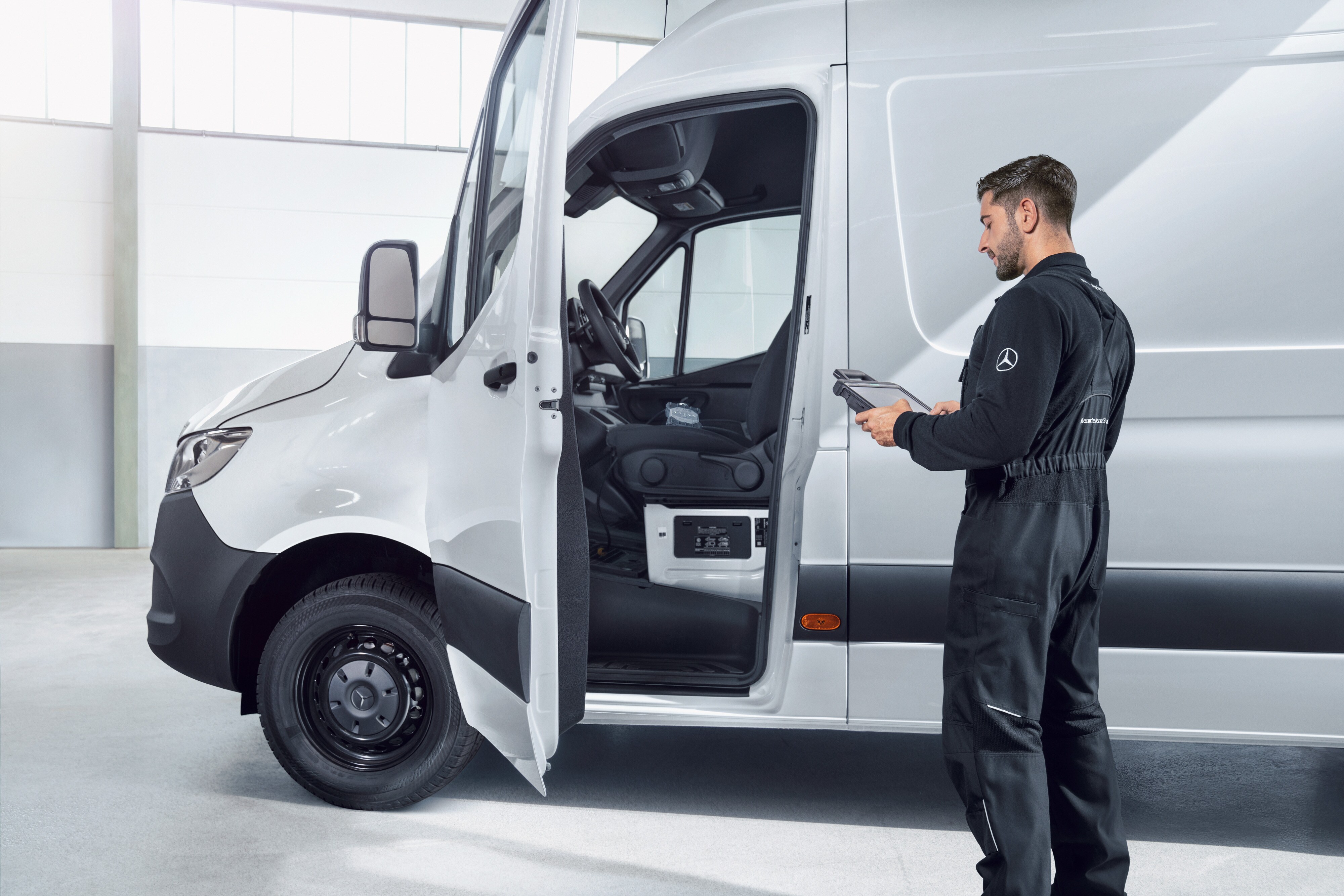 Jakość | Samochody dostawcze Mercedes-Benz Mechanik z tabletem w ręku sprawdzający biały samochód dostawczy Mercedes-Benz.