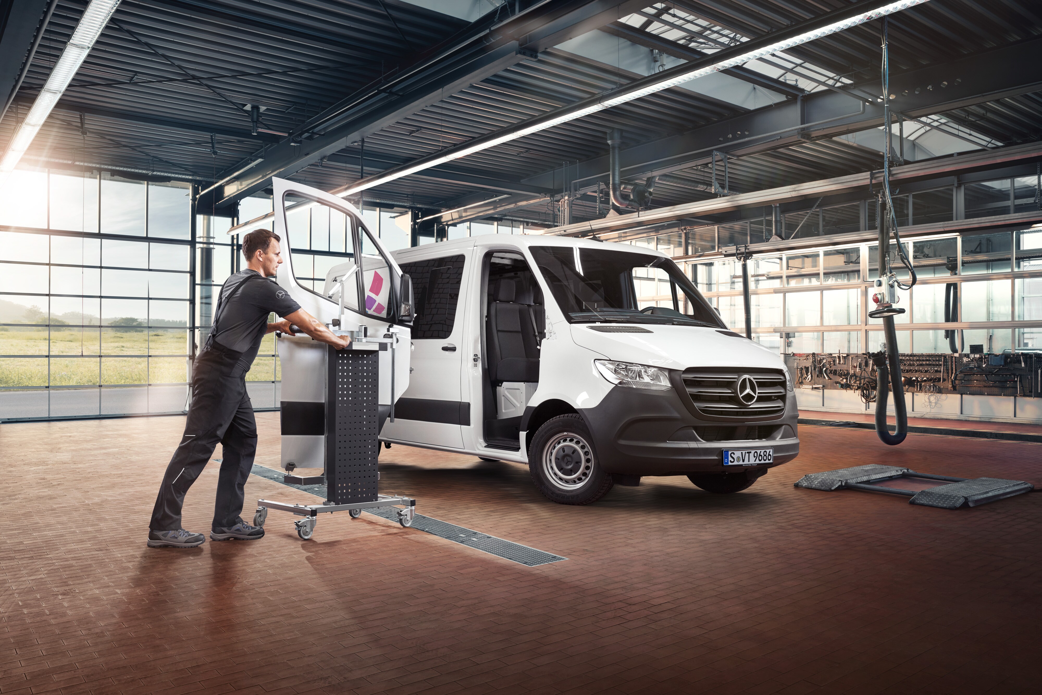 Mercedes-Benz | Przegląd usług | Naprawy Technik wykonuje serwis drzwi od strony pasażera w białym samochodzie dostawczym Mercedes-Benz Sprinter.