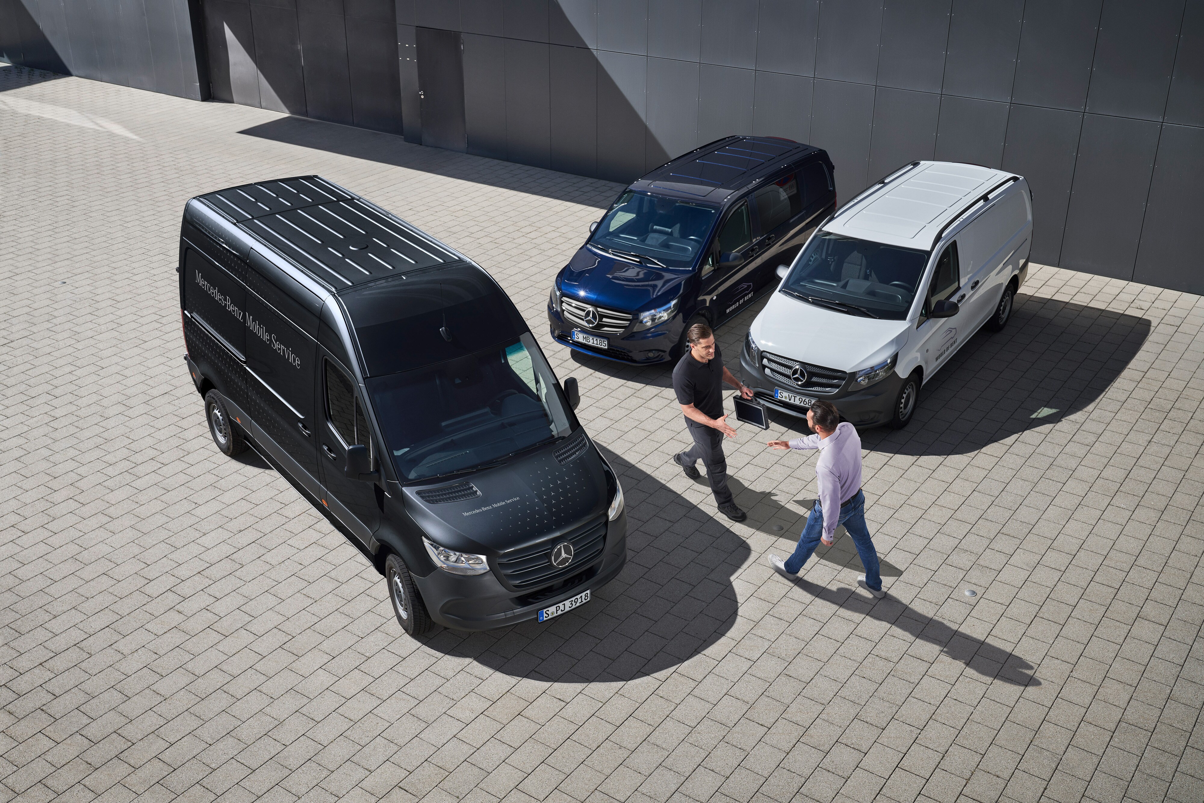 Mercedes-Benz | Przegląd usług | Serwis mobilny Dwóch mężczyzn wita się pomiędzy samochodami dostawczymi Mercedes-Benz.