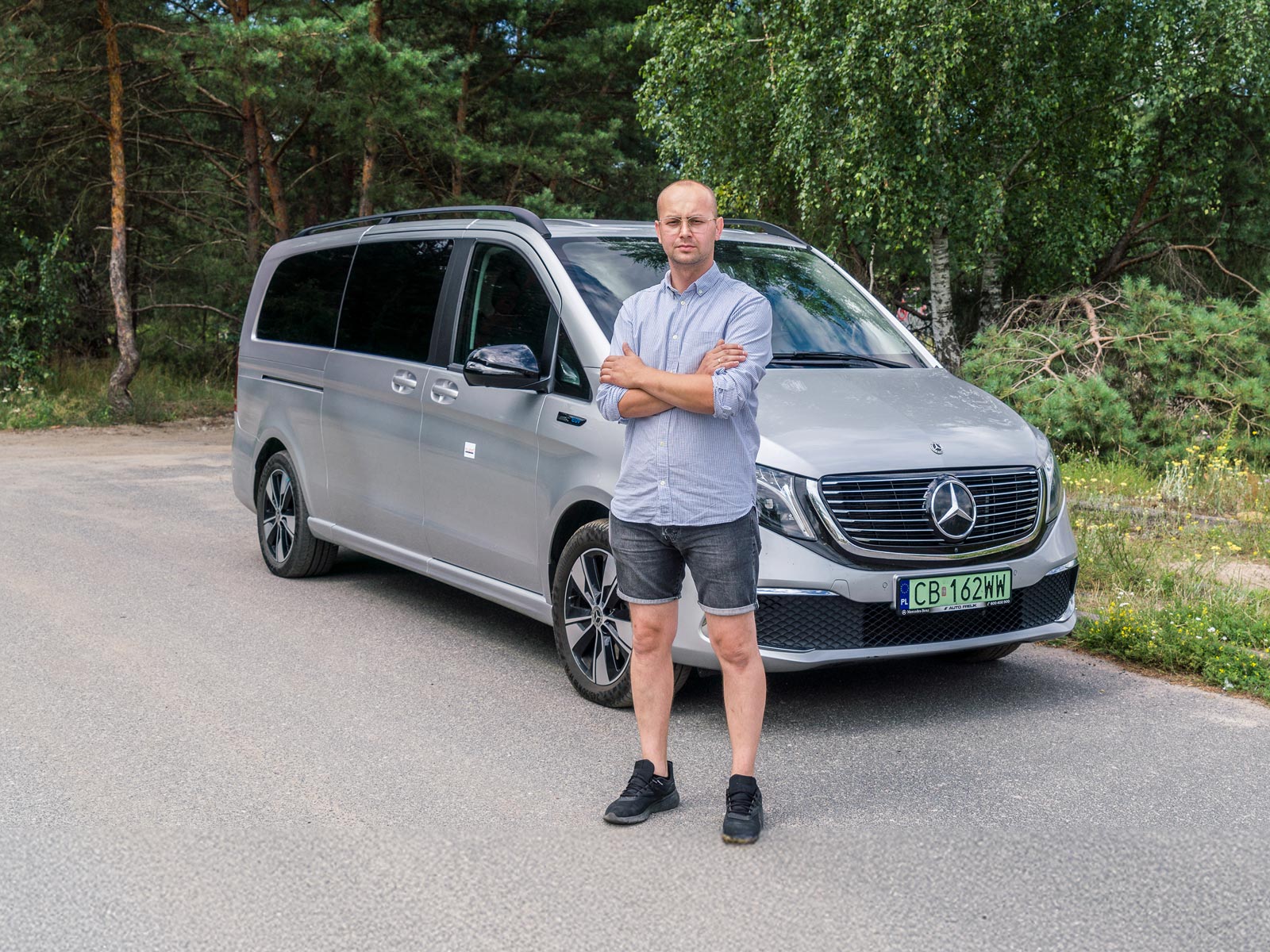 Mercedes-Benz EQV w ośrodku rehabilitacji Neuron Mężczyzna z założonymi rękami stoi przed srebrnym Mercedesem EQV.